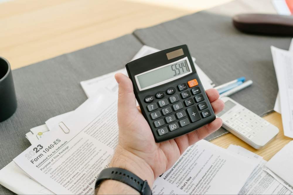 man using calculator on top of forms