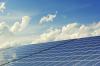 Solar panels lined up under a blue sky.